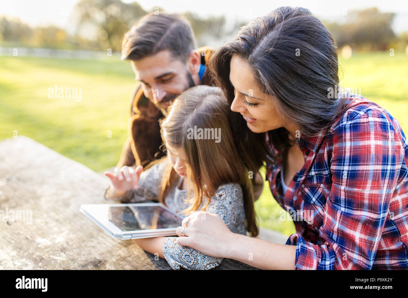 Glückliche Eltern mit Tochter mit digital-Tablette im freien Stockfoto