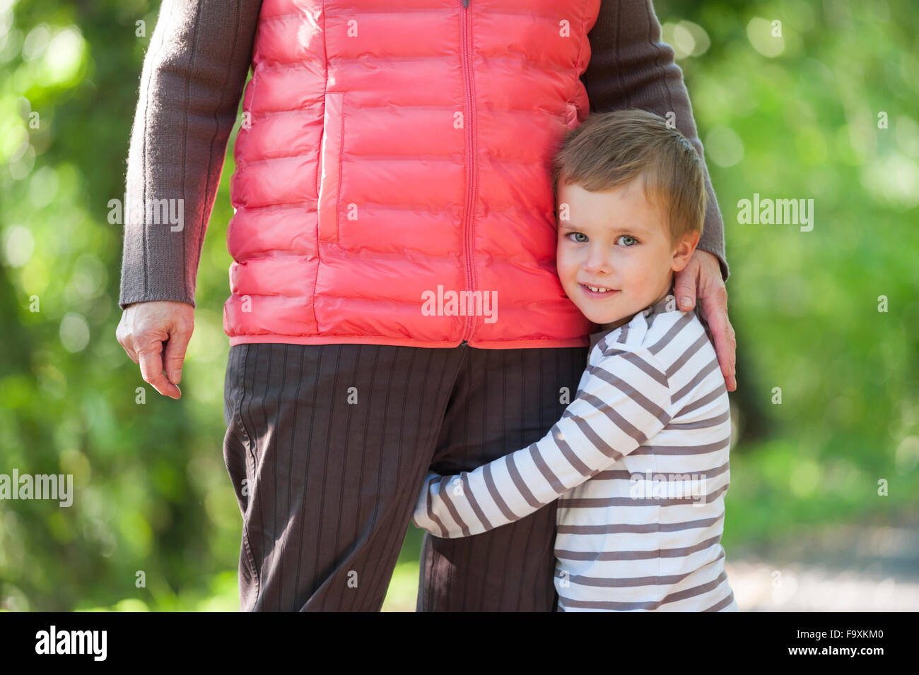 Porträt von lächelnden kleinen Jungen umarmt Bein seiner Großmutter Stockfoto