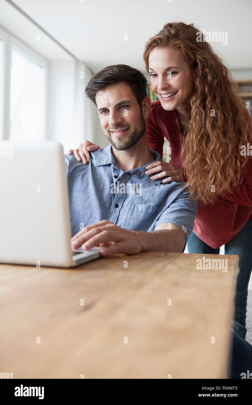 Lächelnde paar zu Hause mit Blick auf laptop Stockfoto