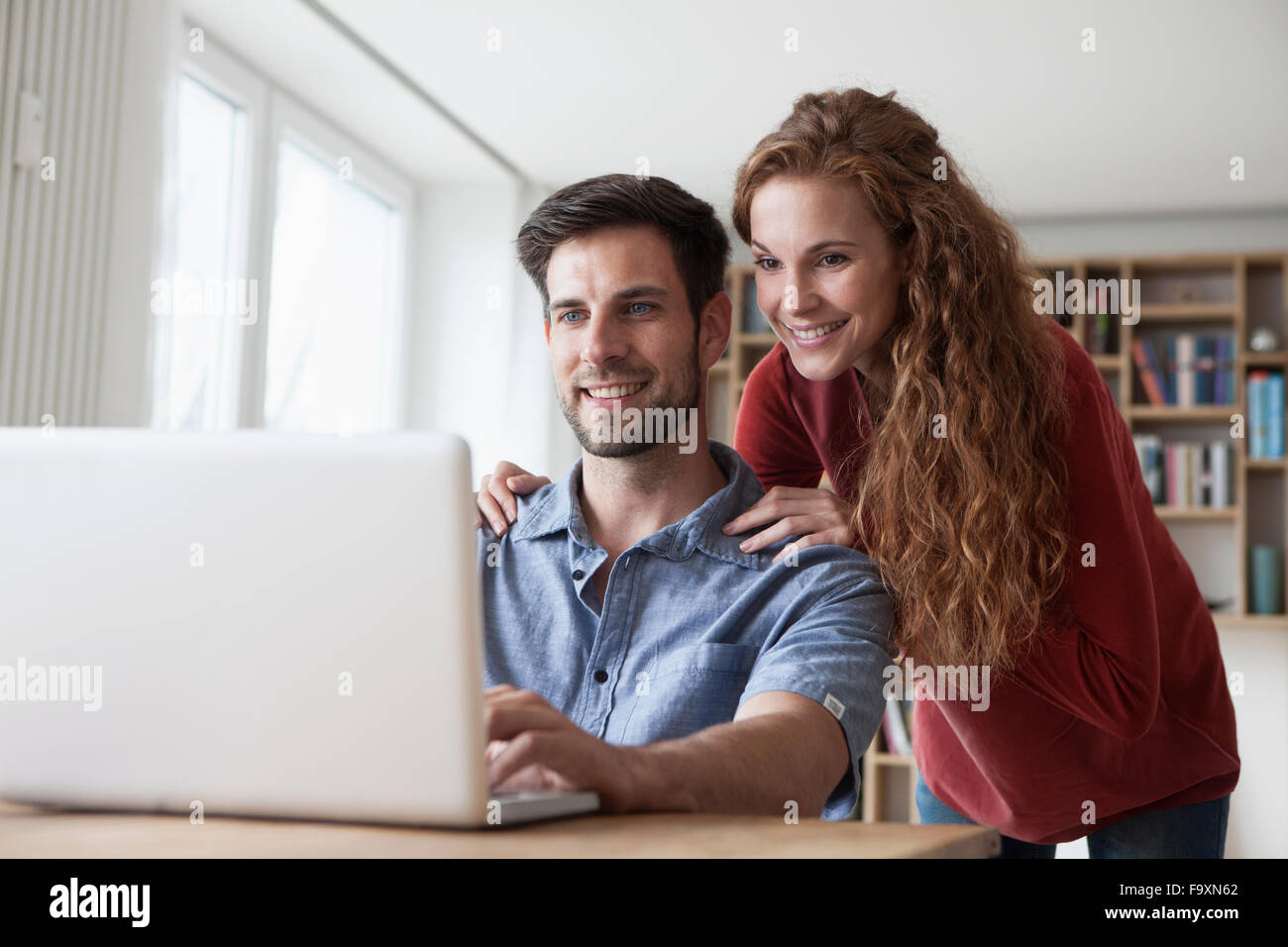Lächelnde paar zu Hause mit Blick auf laptop Stockfoto