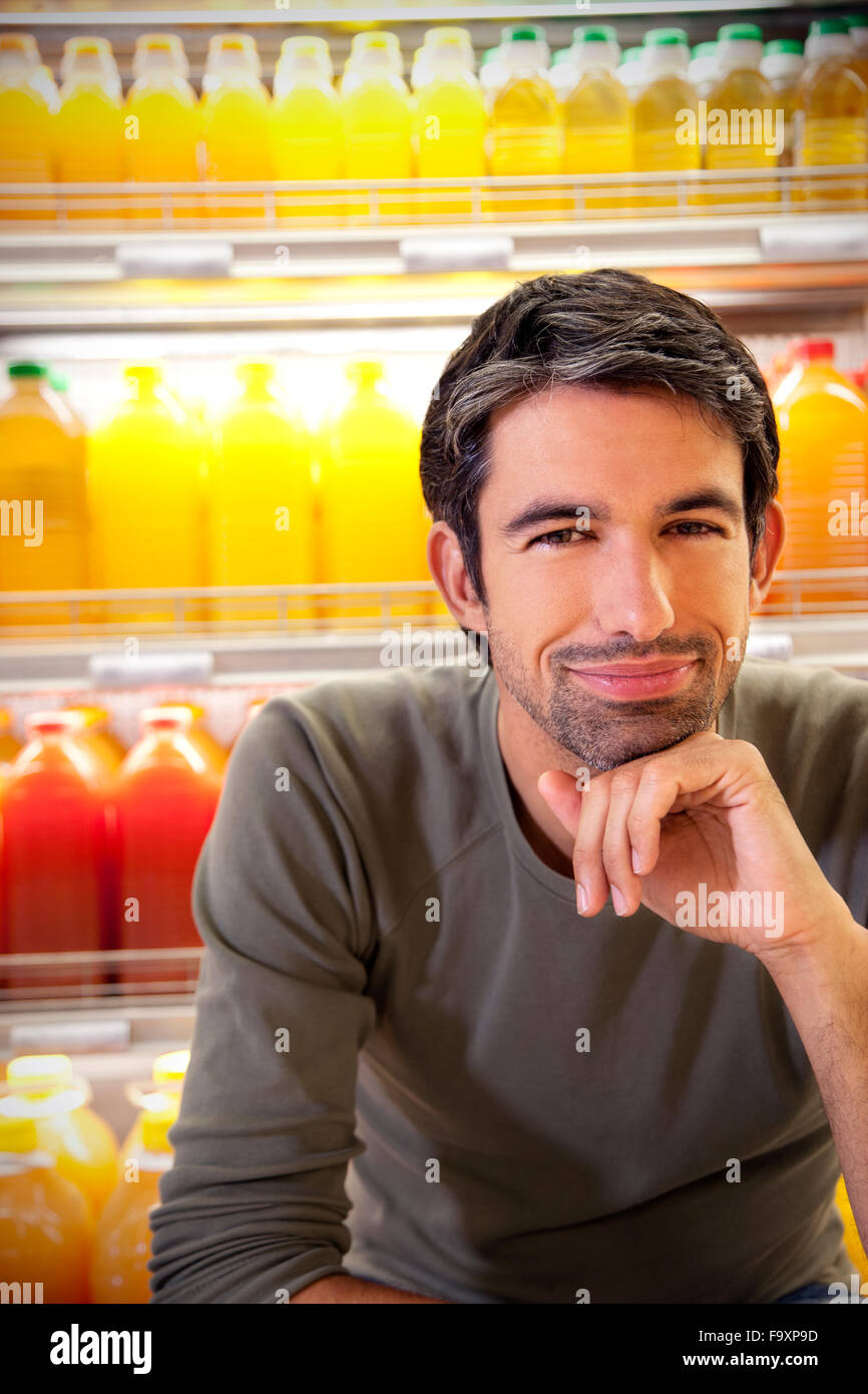 Porträt des lächelnden Menschen sitzen vor Kühlschrank mit Reihen von Saft-Flaschen in einem Supermarkt Stockfoto