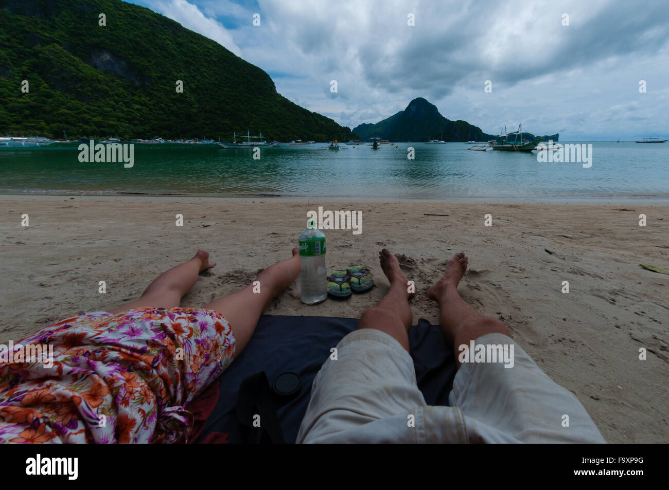 Paar Füße beruhigen Verlegung am Strand mit blaue Meer und die Insel unter Stockfoto