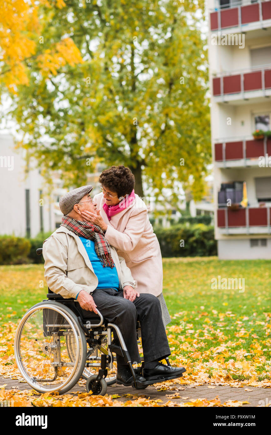 Ältere Frau, die Mann im Rollstuhl betrachten Stockfoto