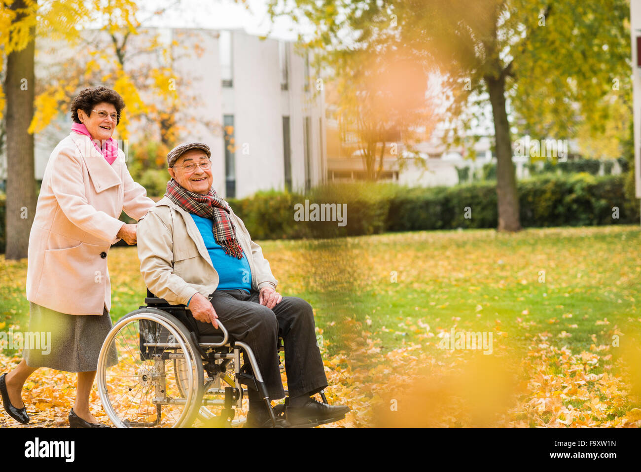 Ältere Frau, die Mann im Rollstuhl schieben Stockfoto