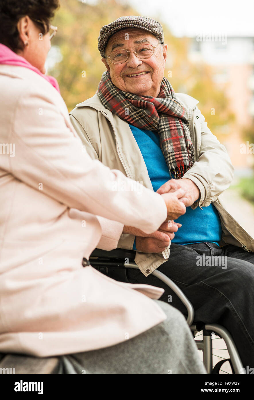 Senior Mann im Rollstuhl, die Hand in Hand mit Frau auf Bank Stockfoto