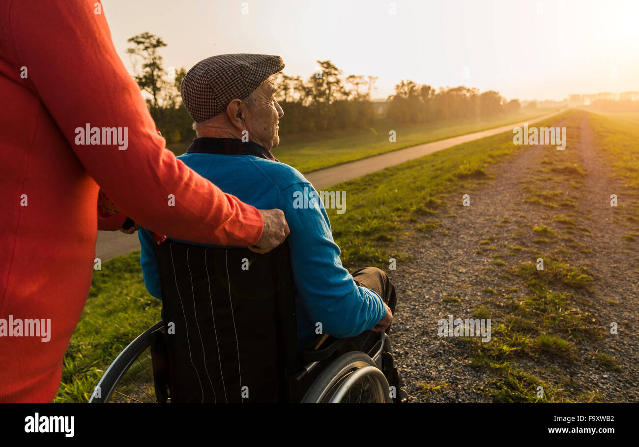 Ältere Frau schob Mann im Rollstuhl in der Natur Stockfoto