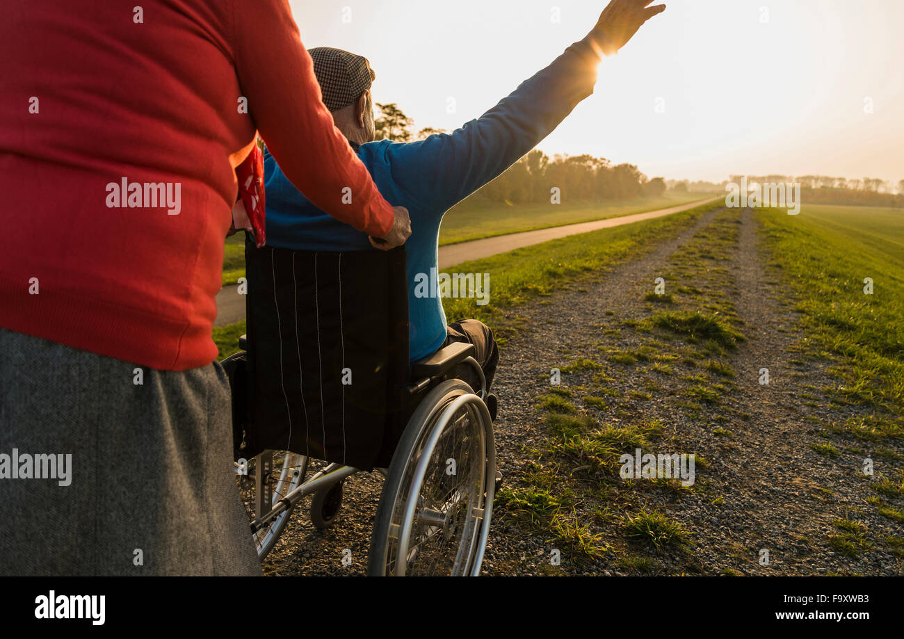 Ältere Frau schob Mann im Rollstuhl in der Natur Stockfoto