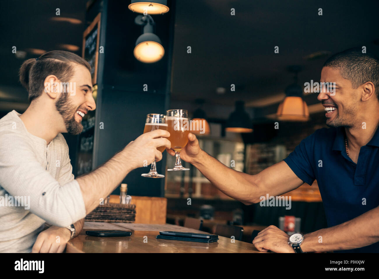 Zwei glückliche Männer in einer Bar klirrendes Biergläser Stockfoto