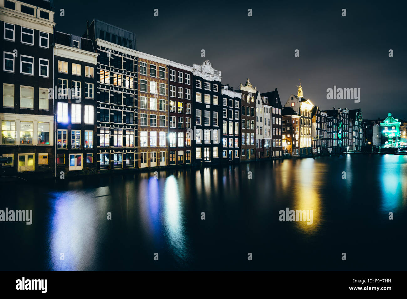 Gebäude entlang der Damrak Kanal in der Nacht in Amsterdam, Niederlande. Stockfoto