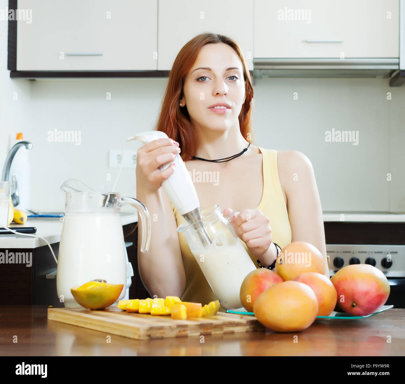 Frau macht frischen Milch cocktail mit Blender von Mango am heimischen Küche Stockfoto