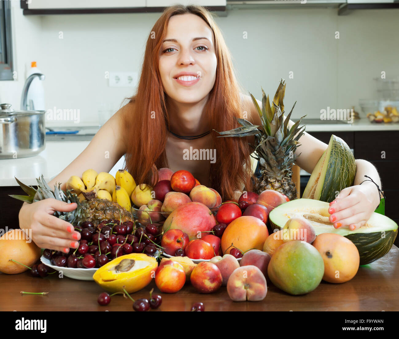 Glücklich langhaarige Mädchen mit Haufen von Obst in der Küche zu Hause Stockfoto