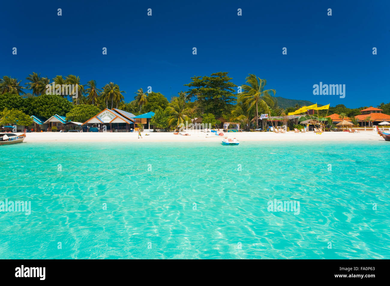 Touristen legen auf den reinen weißen Sand vor Badeorte und eine ruhige türkisblaue kristallklare Meer Stockfoto