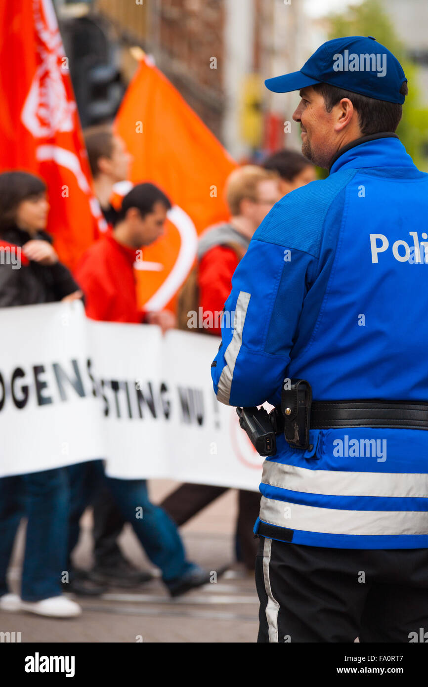 Hinter Blick auf freundliche Banner jovial, Lachen flämischen Polizist lächelnd, wacht über Demonstranten mit Fahnen, am Maifeiertag Stockfoto