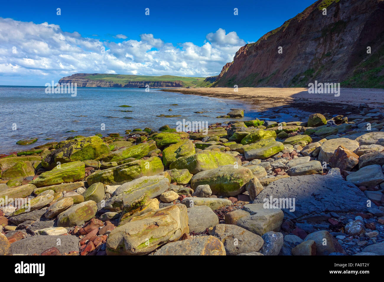 Skinningrove Strand, felsigen Vordergrund, Goldstrand und blauer Himmel, North Yorkshire Stockfoto