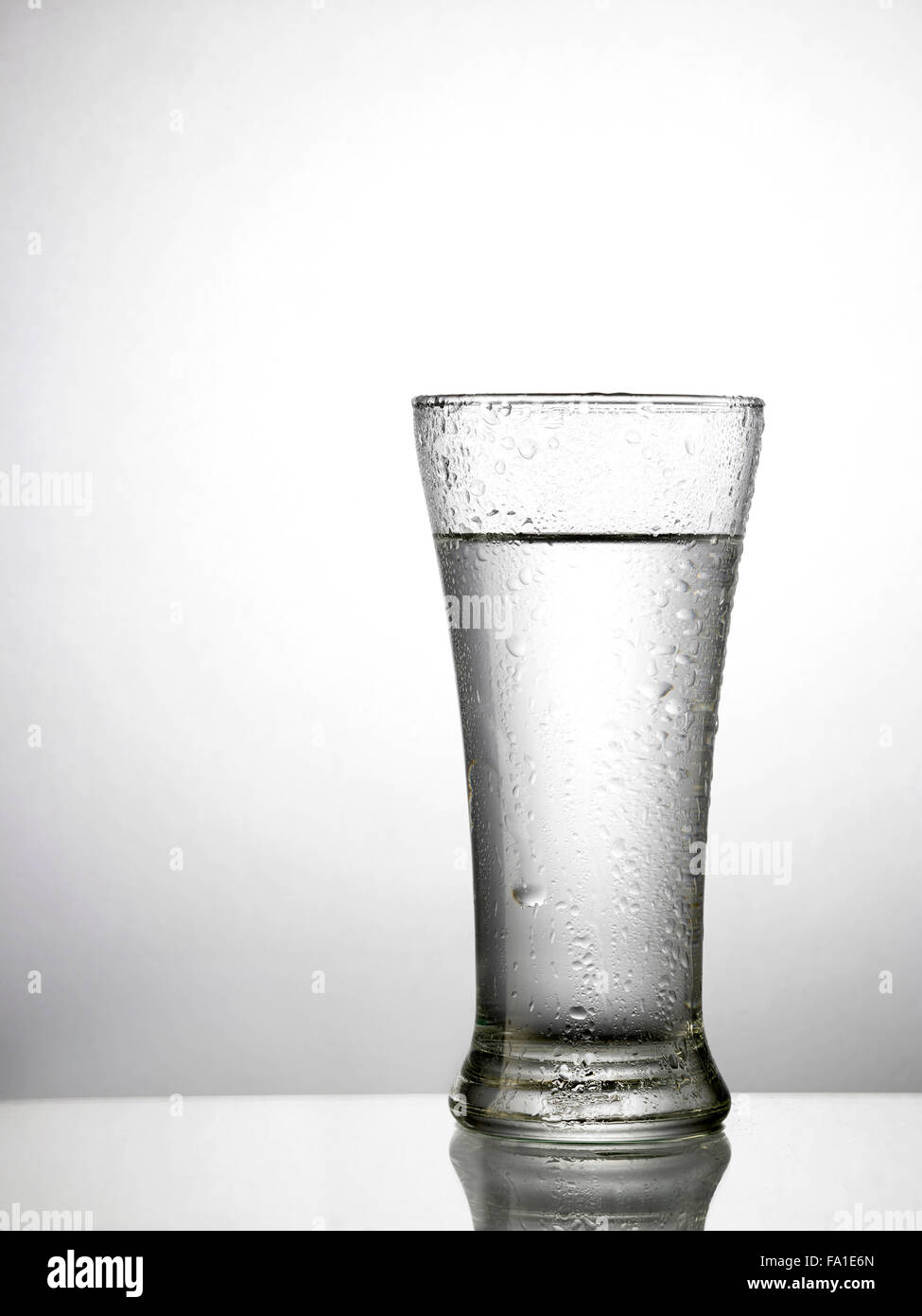 Glas Wasser auf Glastisch Stockfoto