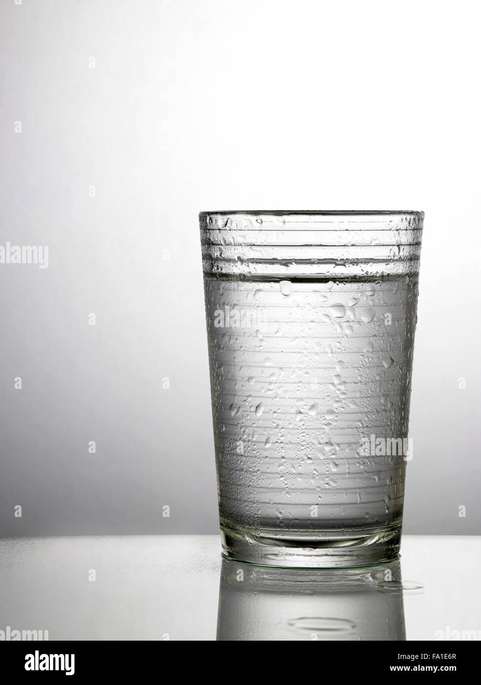 Glas Wasser auf Glastisch Stockfoto