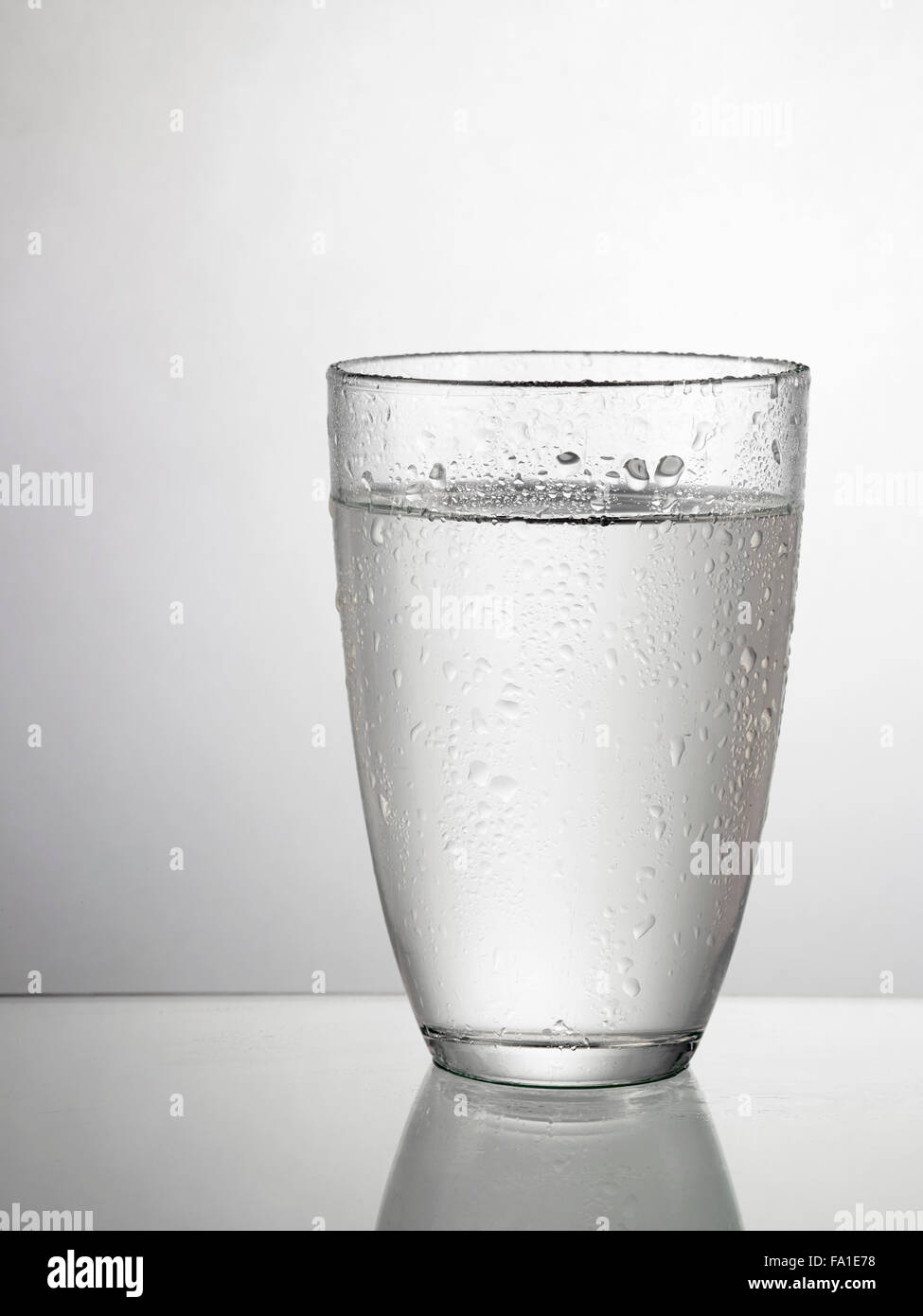 Glas Wasser auf Glastisch Stockfoto