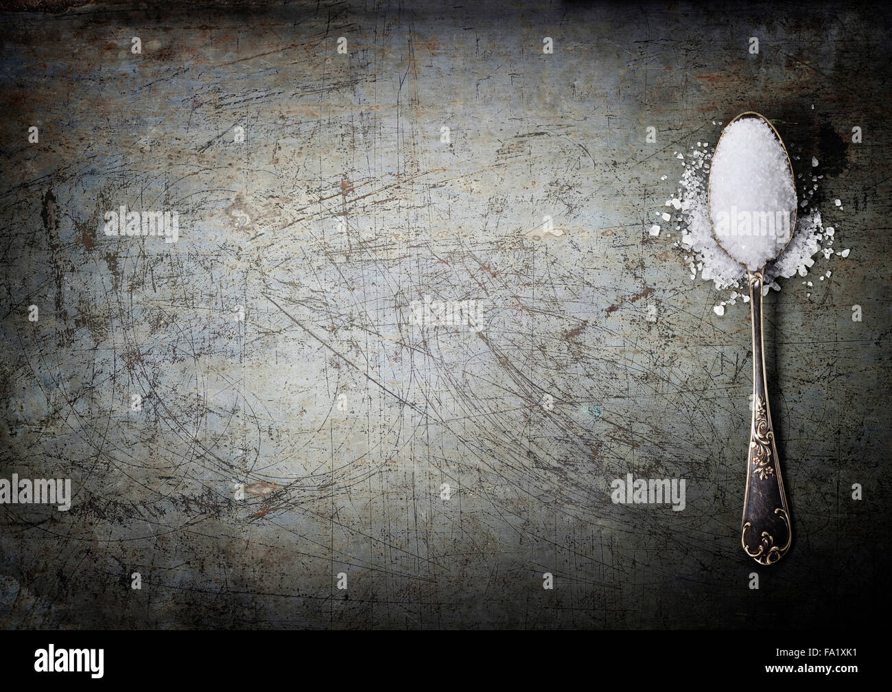 silberner Löffel gefüllt mit Salz auf Rustick Hintergrund Stockfoto