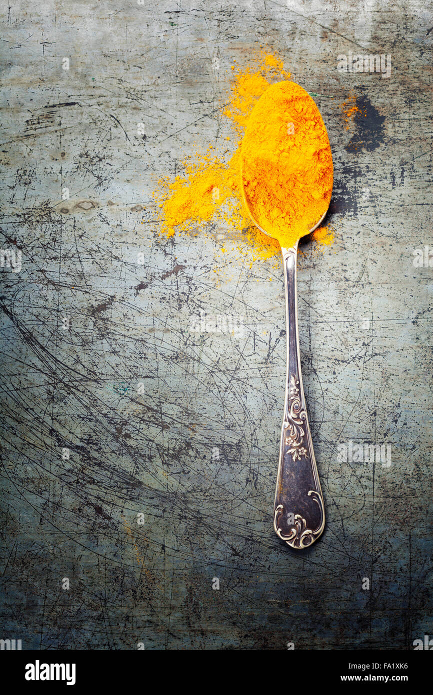 Hellen Gewürzen, verschüttete Currypulver und Löffel auf rustikale Metall Hintergrund Stockfoto