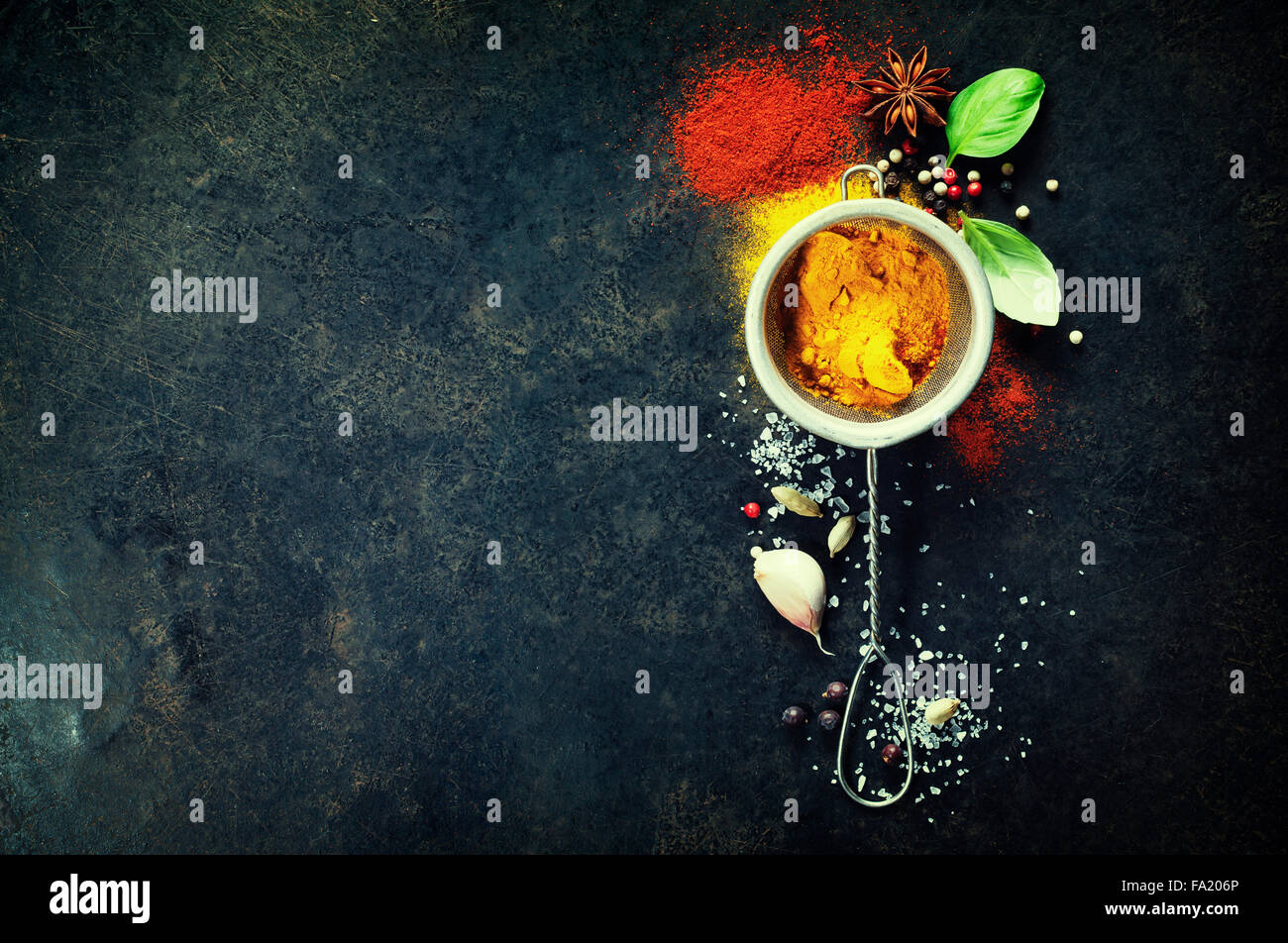 Kräuter und Gewürze Auswahl (Kurkuma, Paprika, Basilikum, Salz, Papper) auf dunklem Hintergrund rustikal. Hintergrund-Layout mit Freitext Stockfoto