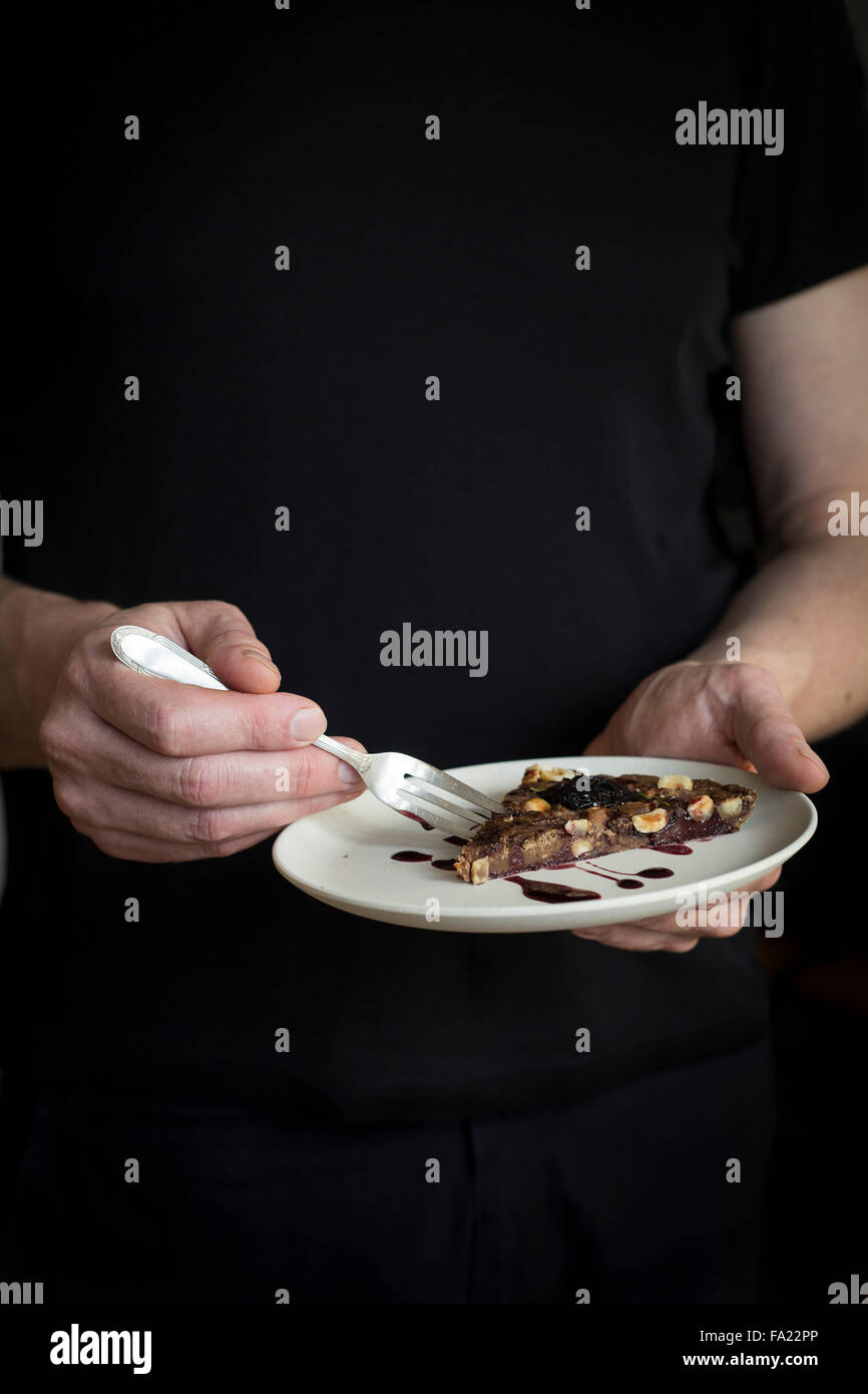 Person einen Teller mit einem Stück Kuchen in den Händen halten. Stockfoto