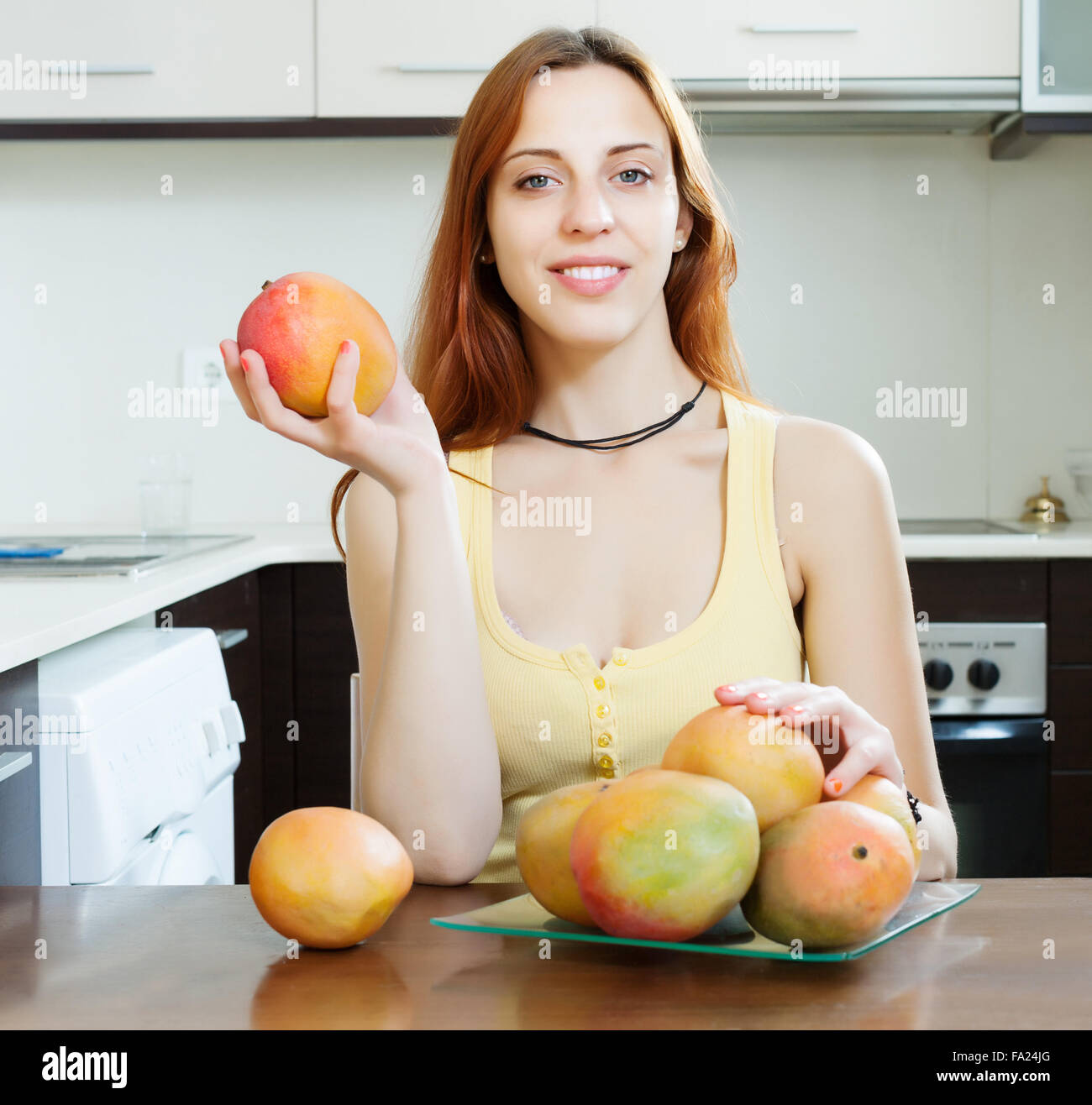 Langhaarige Frau mit Mango in Haus Stockfoto