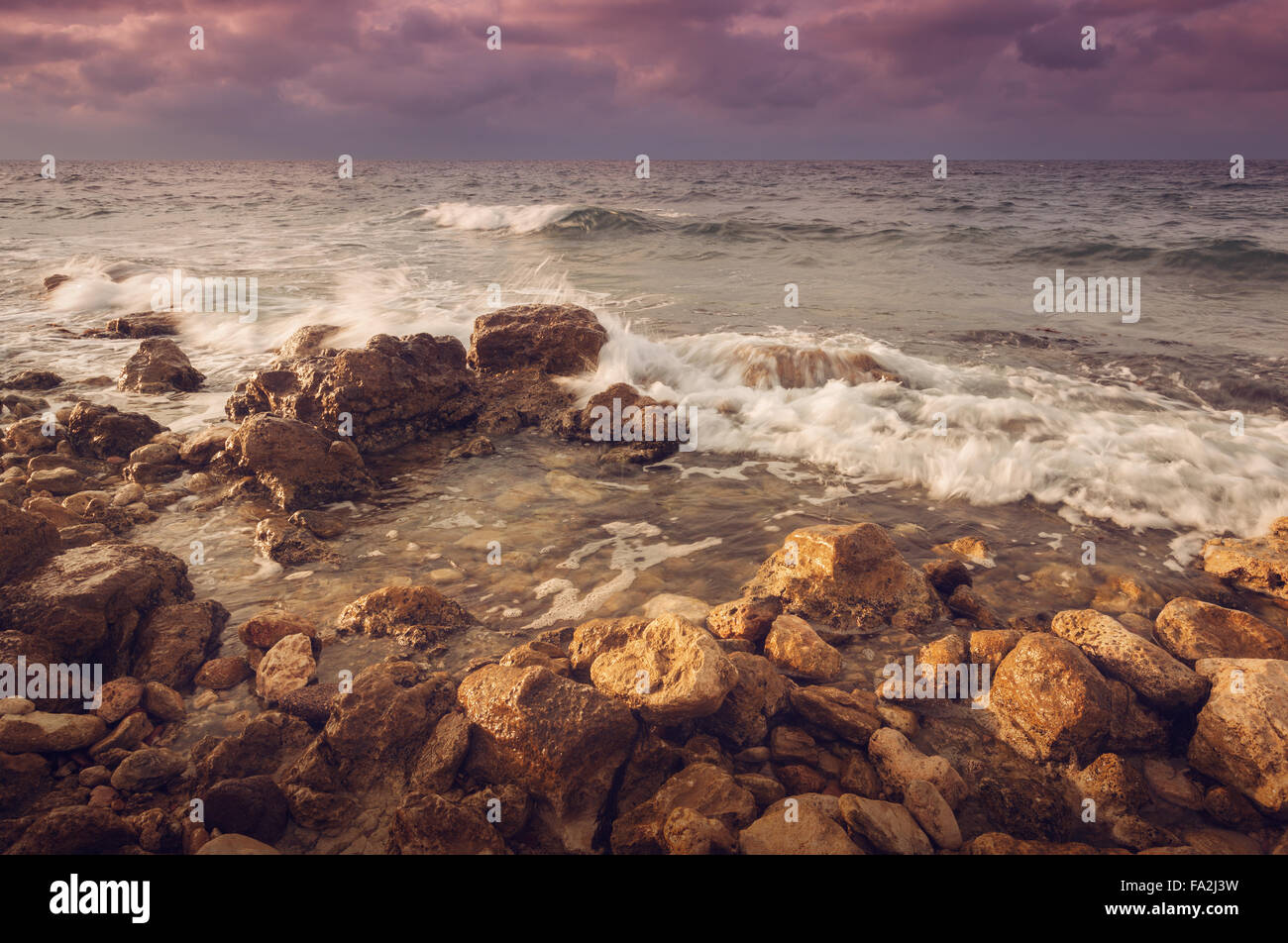 Wellen des Meeres mit Felsen am Strand bei Sonnenuntergang. Partyinsel Landschaft Stockfoto