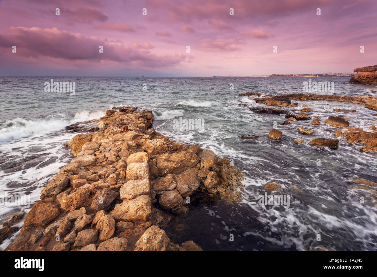 Wellen des Meeres mit Felsen am Strand bei Sonnenuntergang. Schöne Landschaft Stockfoto