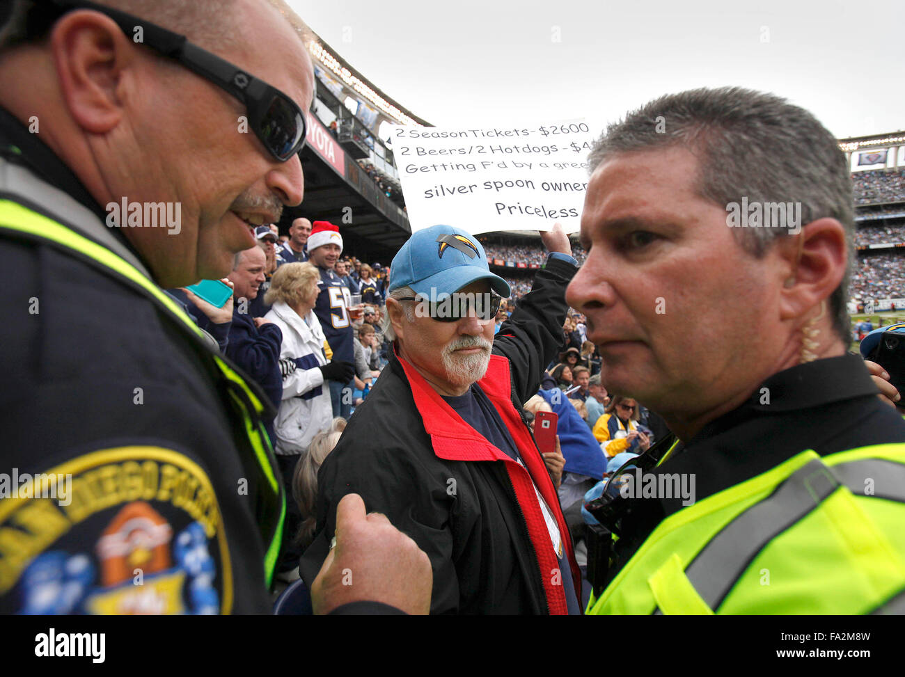 San Diego, CA, USA. 20. Dezember 2015. SAN DIEGO_San Diego letzte Ladegeräte Spiel im Qualcomm Stadium kann auf Sonntag, 20. Dezember 2015 gespielt worden sein. Fans fuhr den Wagen, um das Spiel zu bekommen. | San Diego Polizeioffiziere flankieren Brent Mote von Burbank, aber ursprünglich aus San Diego, nachdem einige Fans beschwerten sich über seine Zeichen eindeutig ungünstigen mit den Ladegeräten und in bestimmten Inhaber Dean Spanos ist. Nach einer Diskussion wurde ihm erlaubt, seine Zeichen zu halten. Er ist ein 45-Jahr-Ticket-Inhaber, die diesem Streifen als 17-Year-Old in der High School begann. | John Gastaldo/San Diego Union-Tribune (Kredit-Bild: © Jo Stockfoto