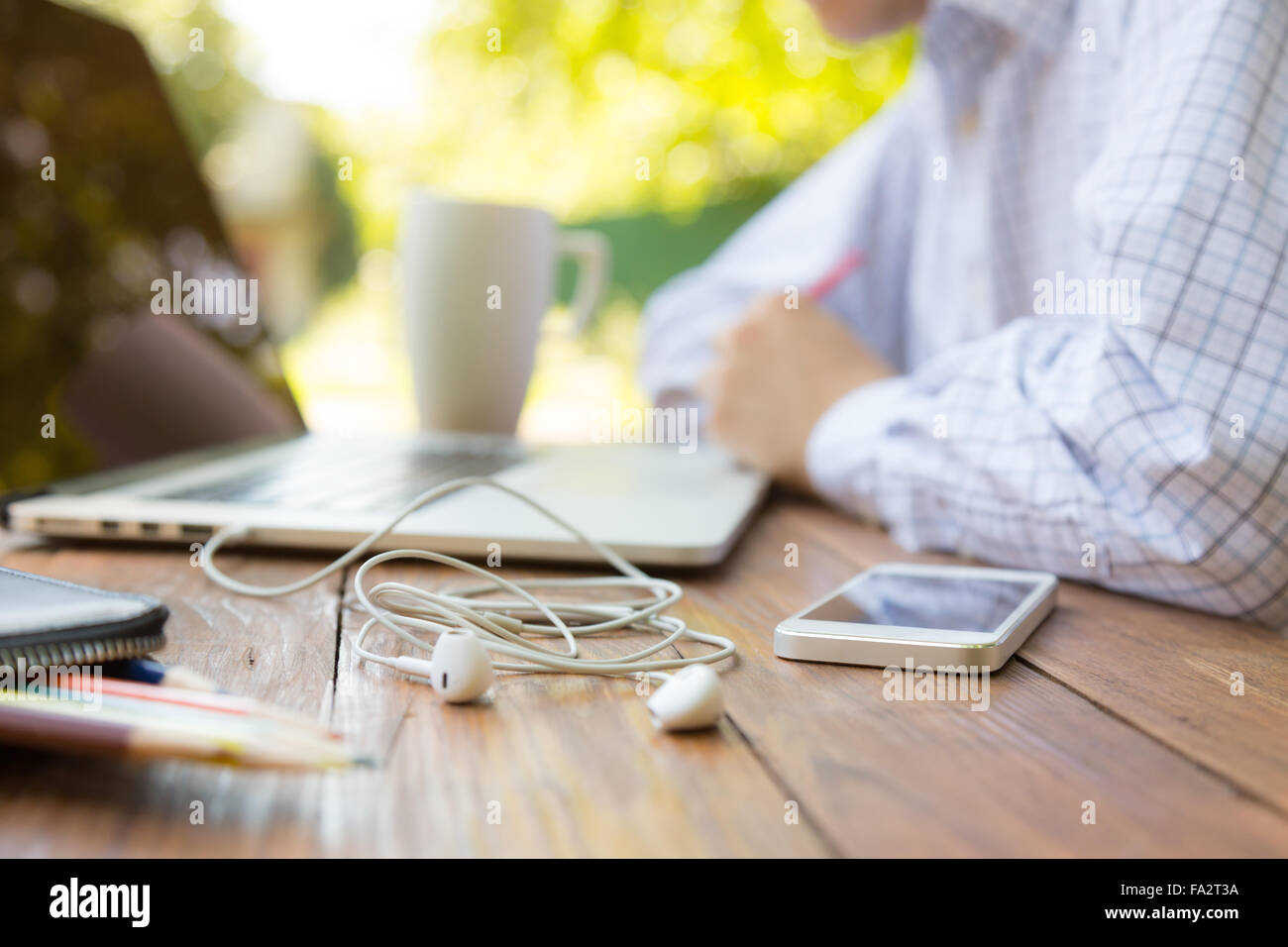 Entkam der Büro Mann sitzt am natürlichen Land Stil Schreibtisch aus Holz mit elektronischen Geräten Stockfoto