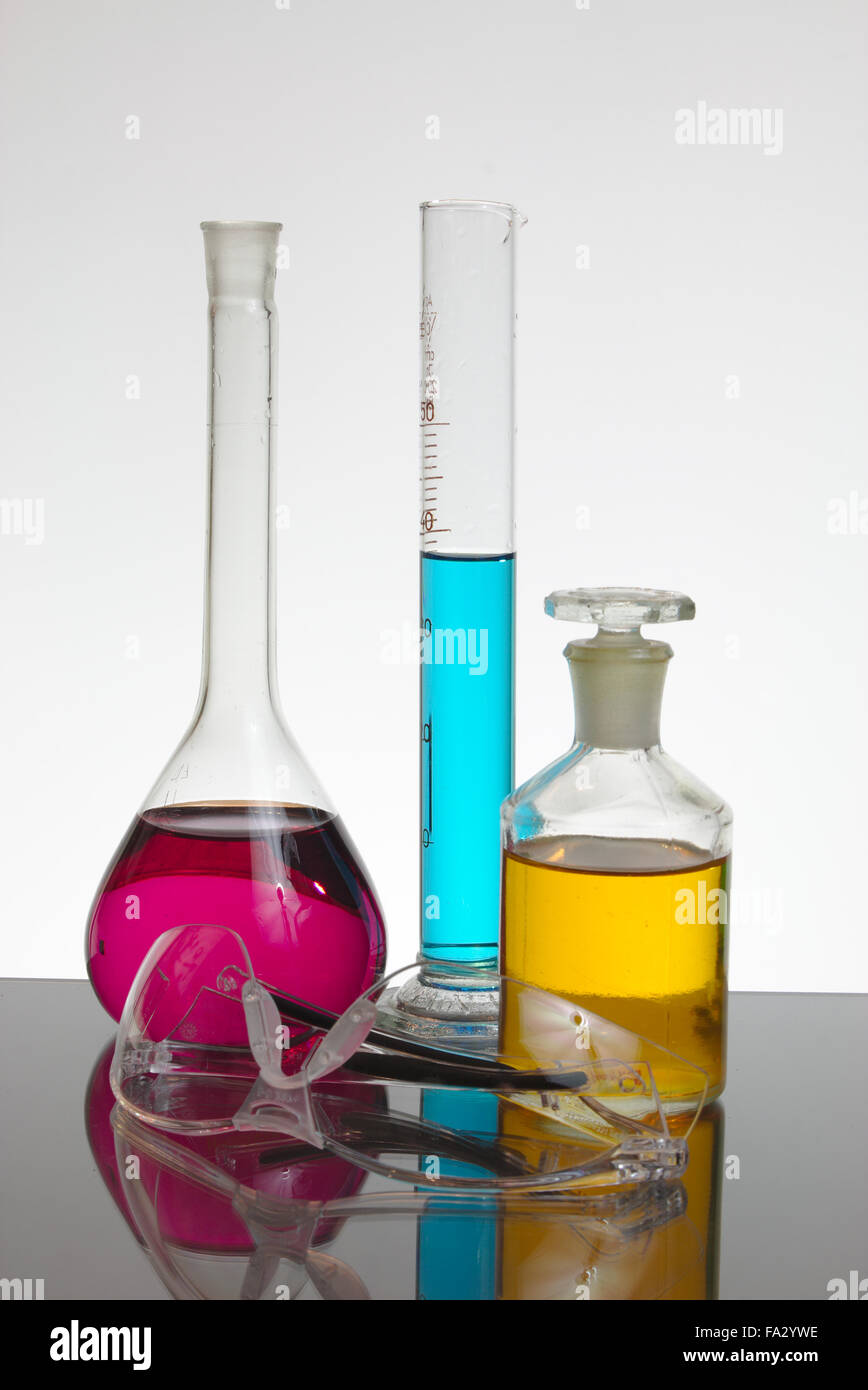 Laborglas mit Salzlösungen und Schutzbrille. Stockfoto