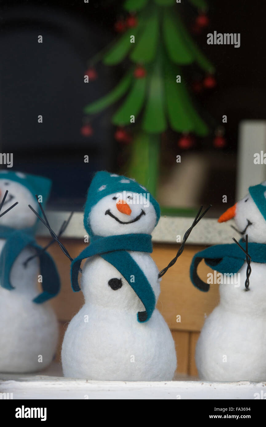 Glücklich lächelnd Weihnachten Schneemänner Puppen in einem Schaufenster. Cotswolds, England Stockfoto