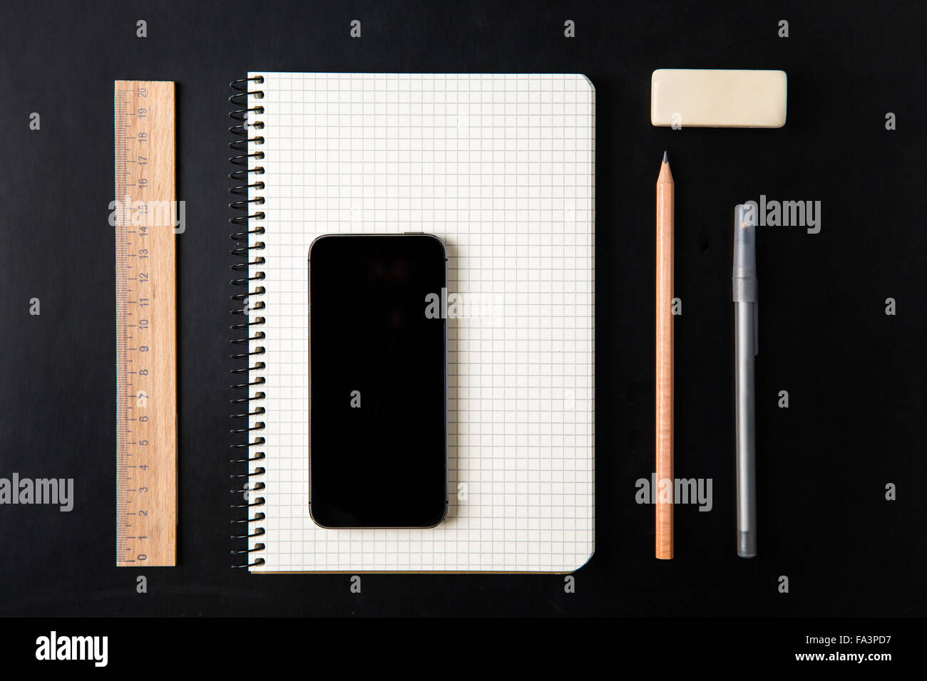 Draufsicht der Schulmaterialien und leerer Bildschirm-Handy auf schwarzem Hintergrund isoliert Stockfoto