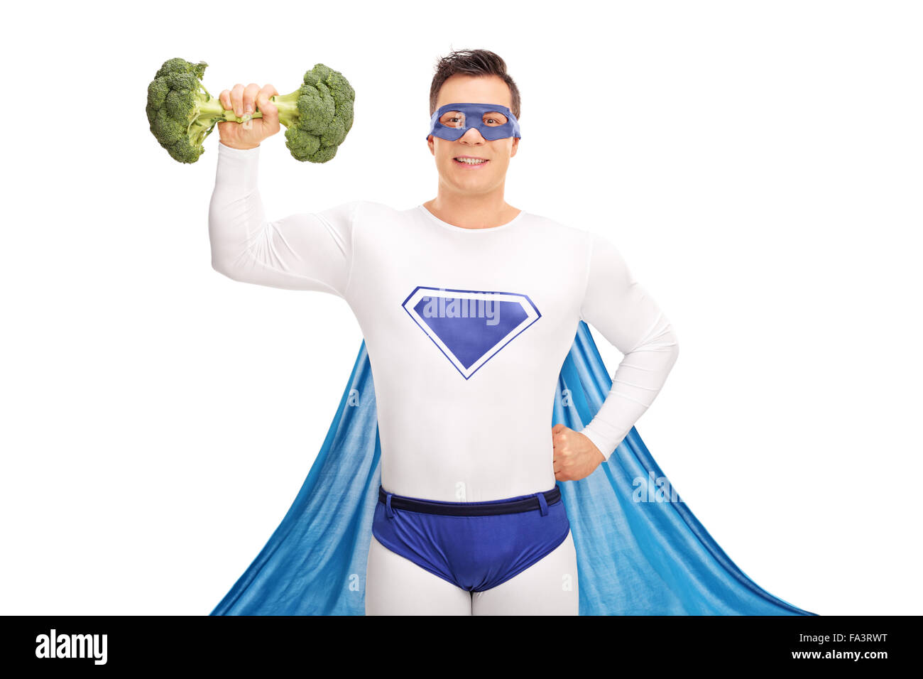 Junger Mann in weißen und blauen Superhelden-Kostüm eine Brokkoli-Hantel  heben und in die Kamera schaut Stockfotografie - Alamy