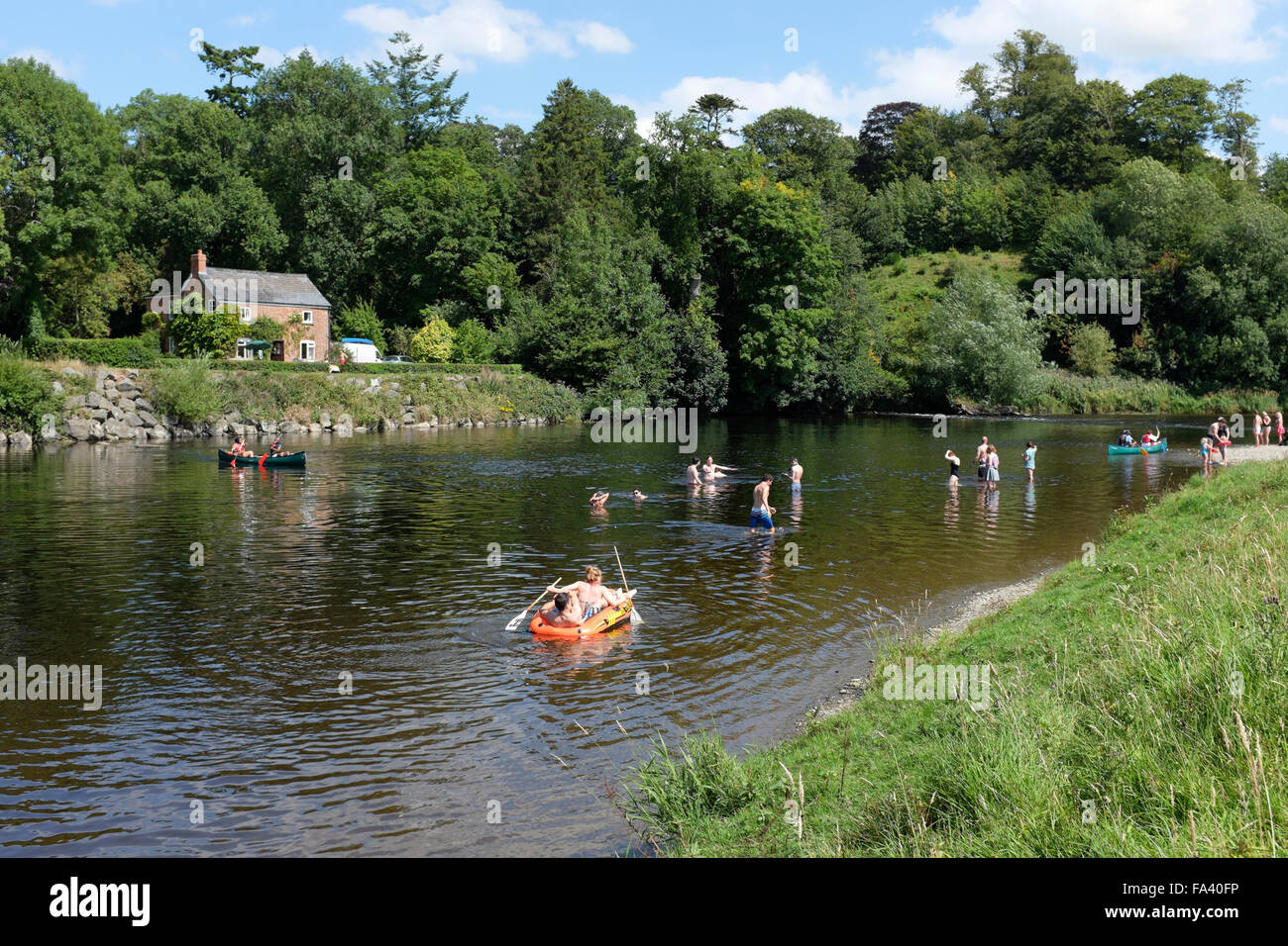 Menschen, die genießen, Rudern, Paddeln und schwimmen auf und in den Fluss Wye am Stadtrand von Hay-on-Wye, Powys, Wales Stockfoto