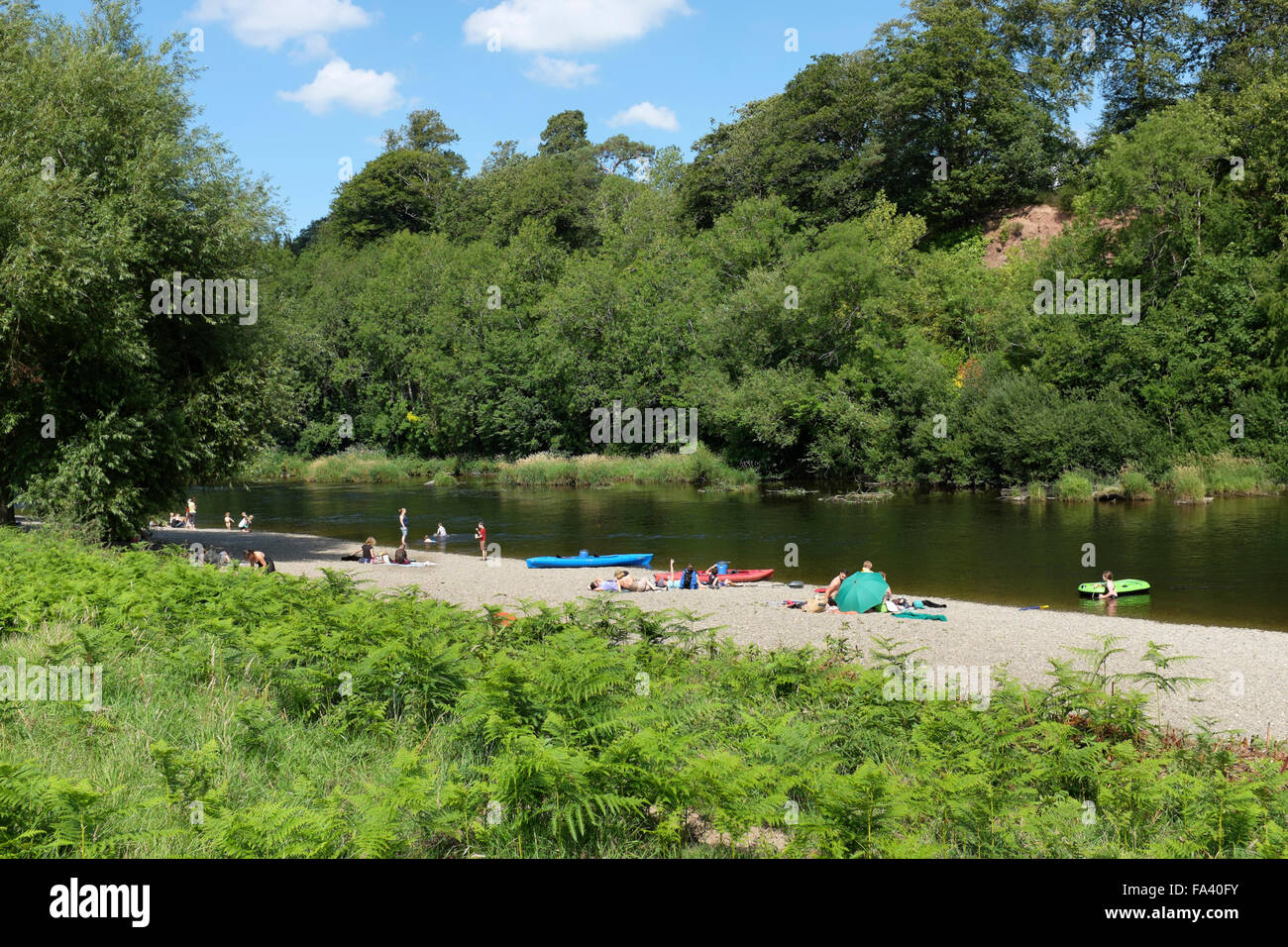 Familien genießen einen Sommertag am Kiesstrand, der bürgerliche Wiese, Hay-on-Wye, Powys, Wales Stockfoto