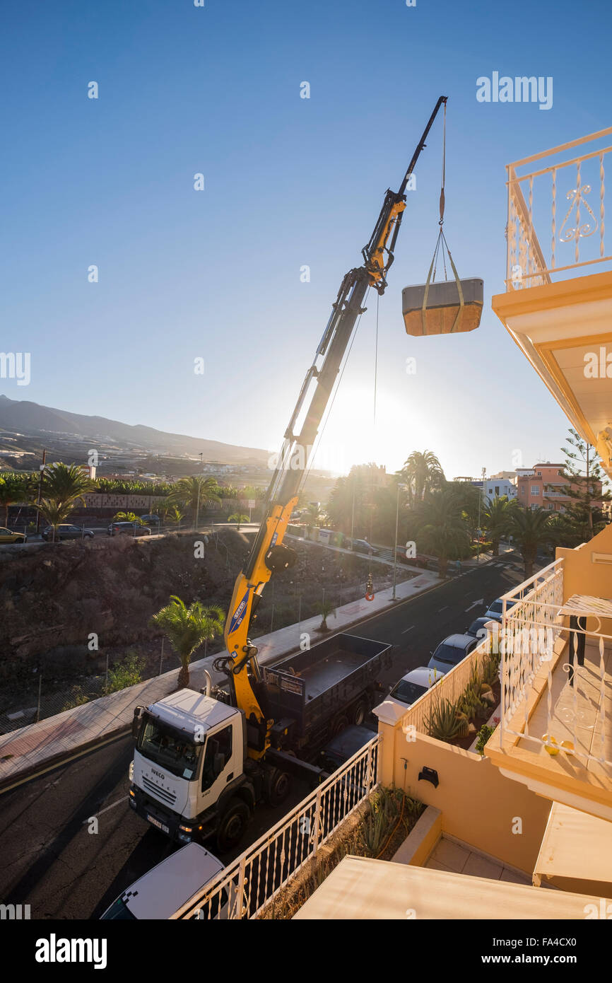 LKW montierte Kran heben einen Whirlpool aus der obersten Etage eines Mehrfamilienhauses, Playa San Juan, Teneriffa, Kanarische Inseln, Spa Stockfoto