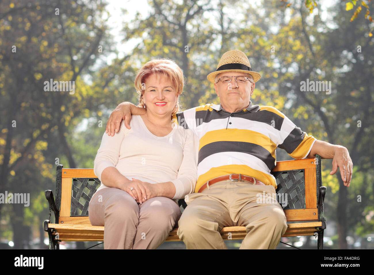 Älteres paar sitzen auf einer Bank im Park und umarmt Stockfoto