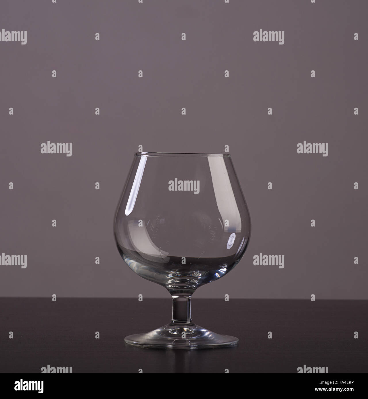 Leere Cognac Glas mit Reflexionen auf grauem Hintergrund Stockfoto