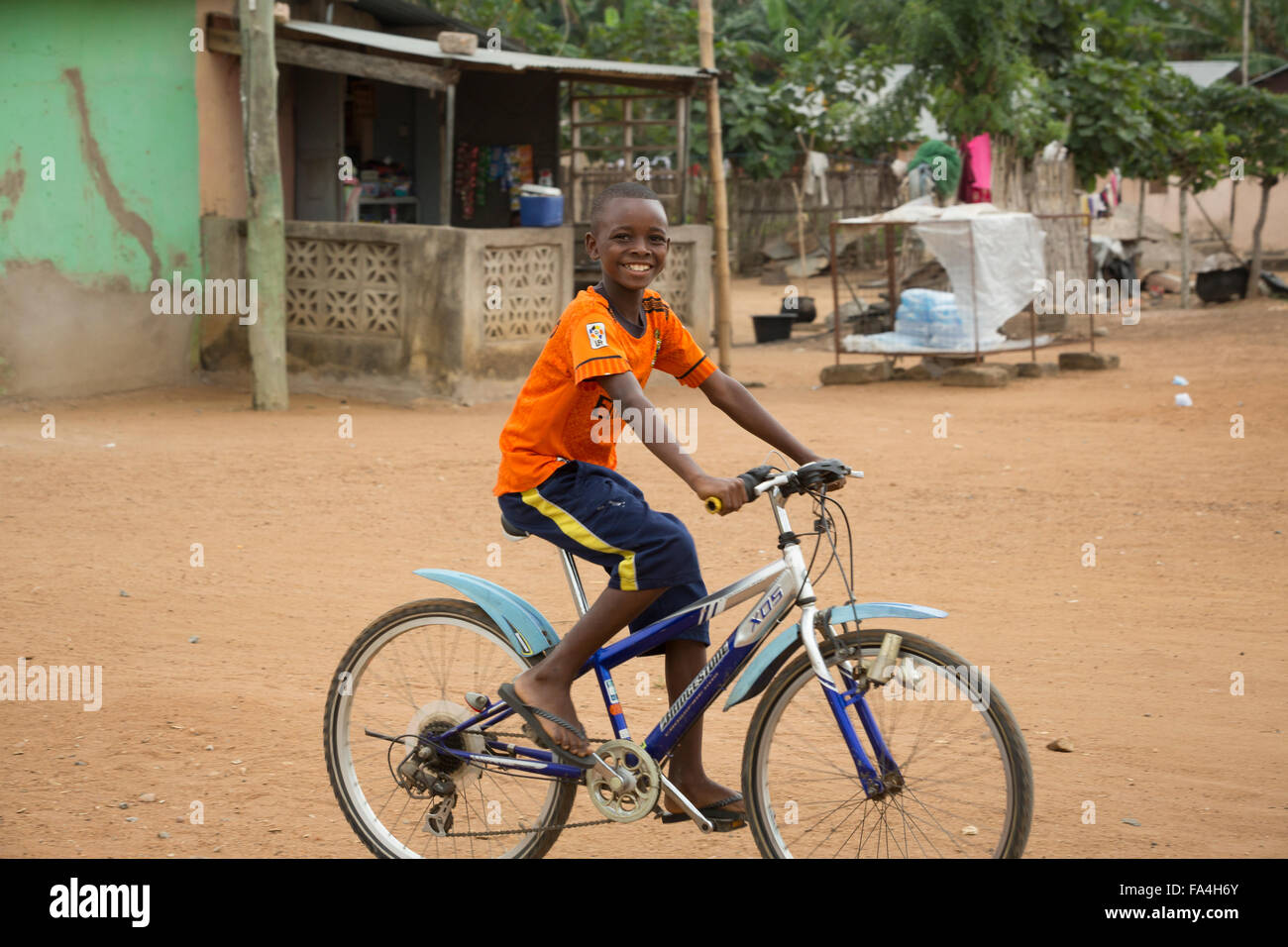 Ein Kind reitet auf seinem Fahrrad durch Fotobi Dorf in SE Ghana. Stockfoto
