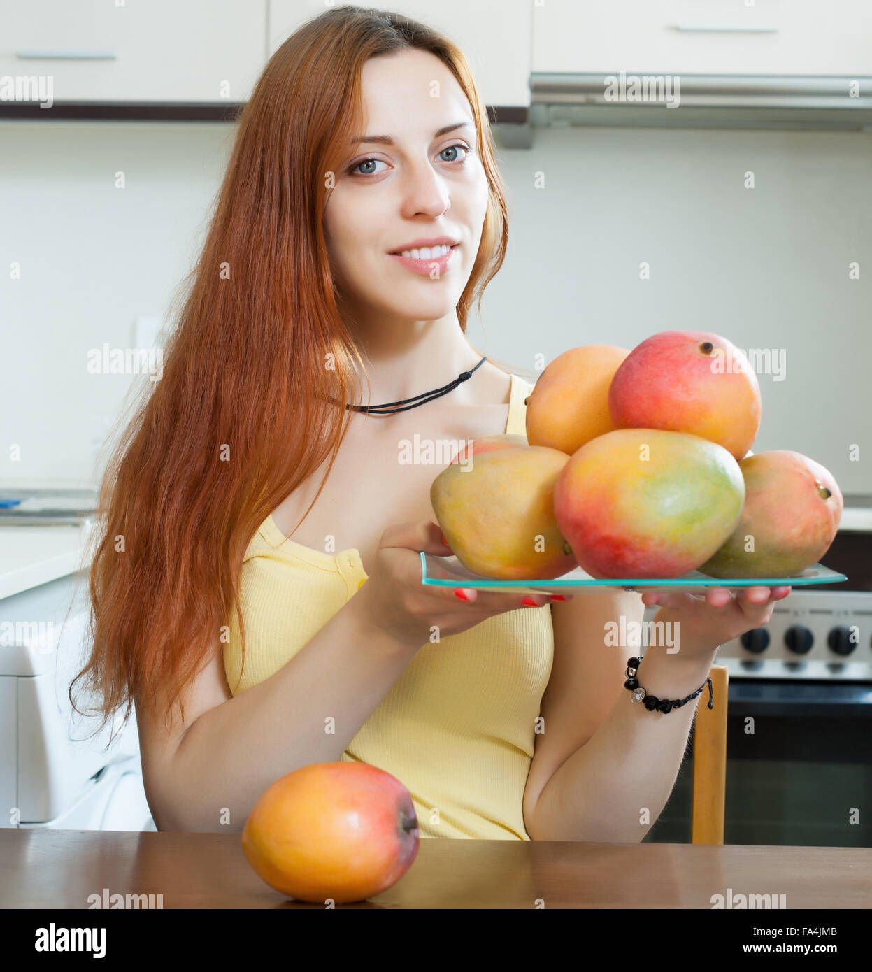 gewöhnliche Frau Halteplatte mit Reife Mango in der Küche zu Hause Stockfoto