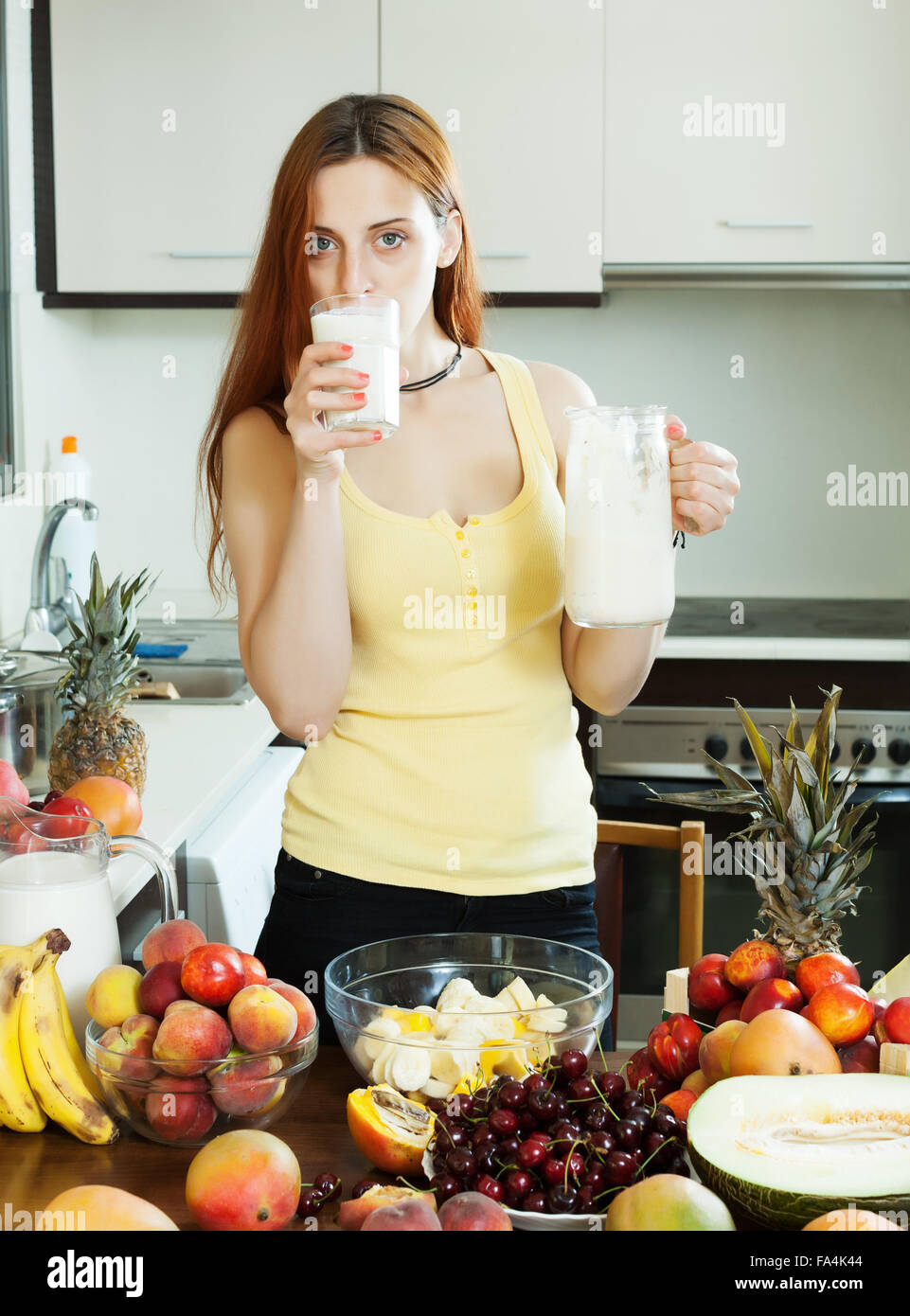 gewöhnliche Frau Milch cocktail mit Früchten am heimischen Küche Stockfoto