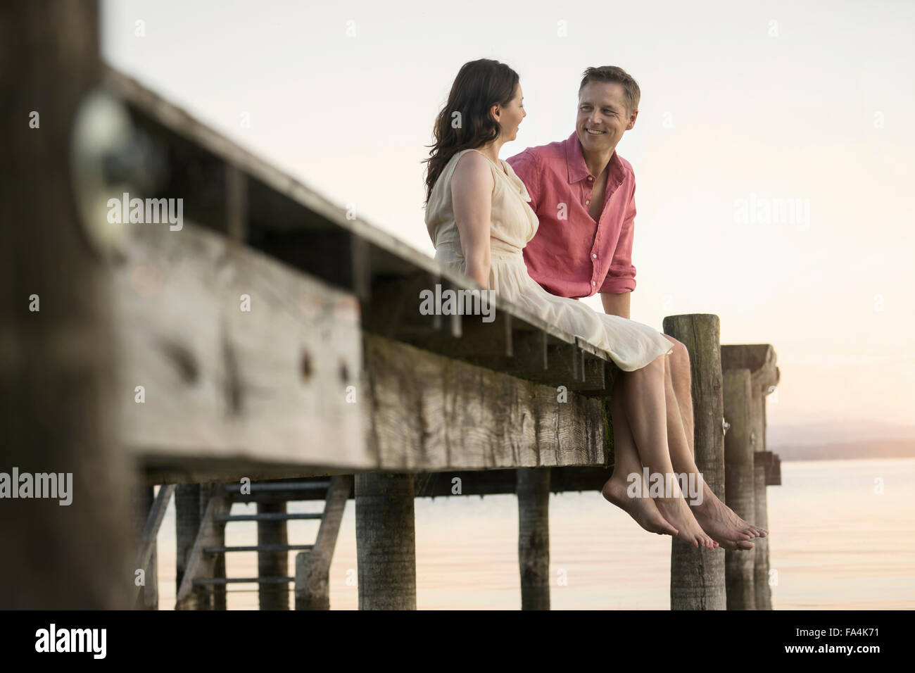 Älteres Paar einander betrachtend und lächelnd auf Pier, Bayern, Deutschland Stockfoto