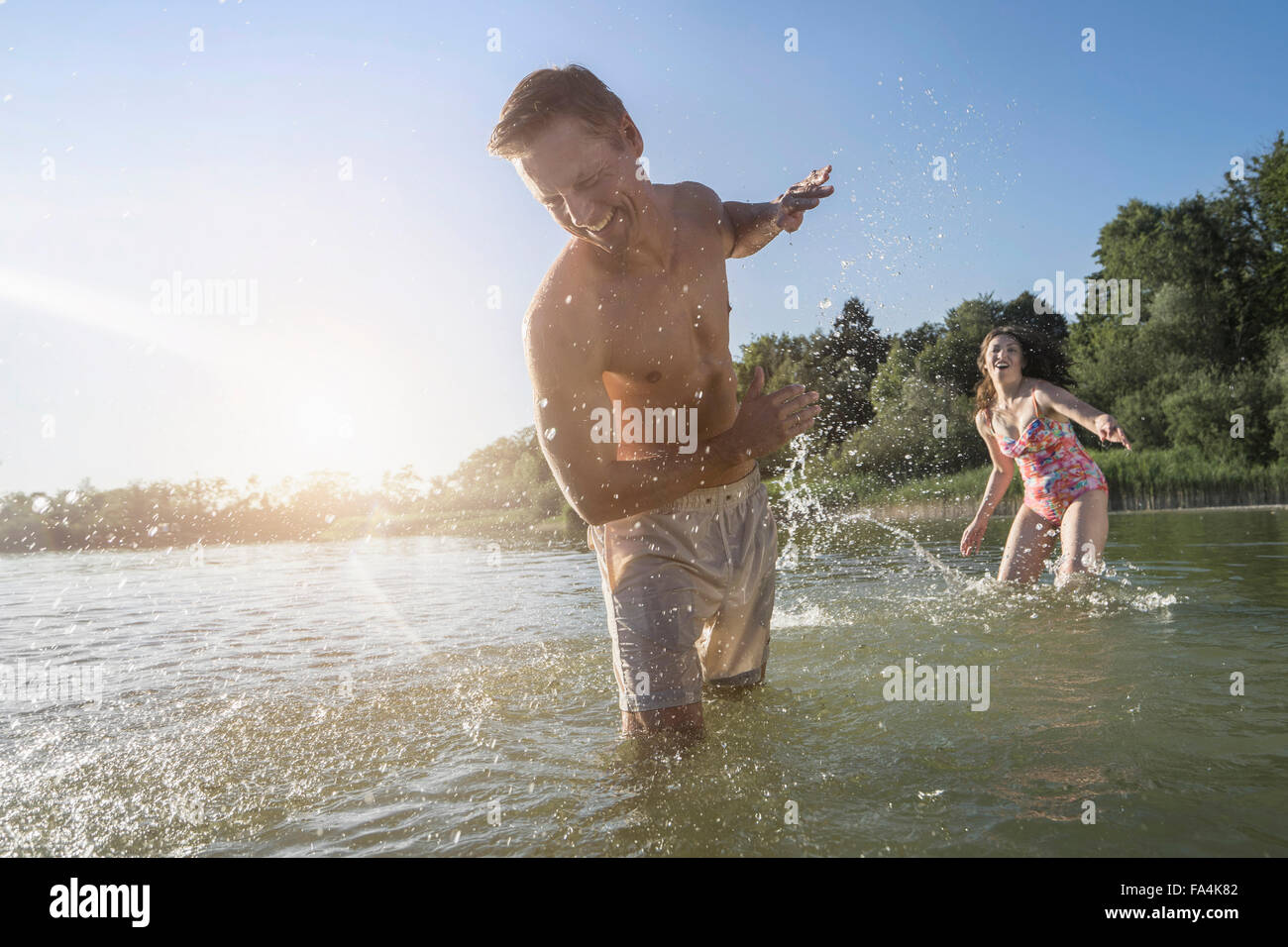 Reife Frau spritzt sich Wasser auf ihr Mann auf See, Bayern, Deutschland Stockfoto