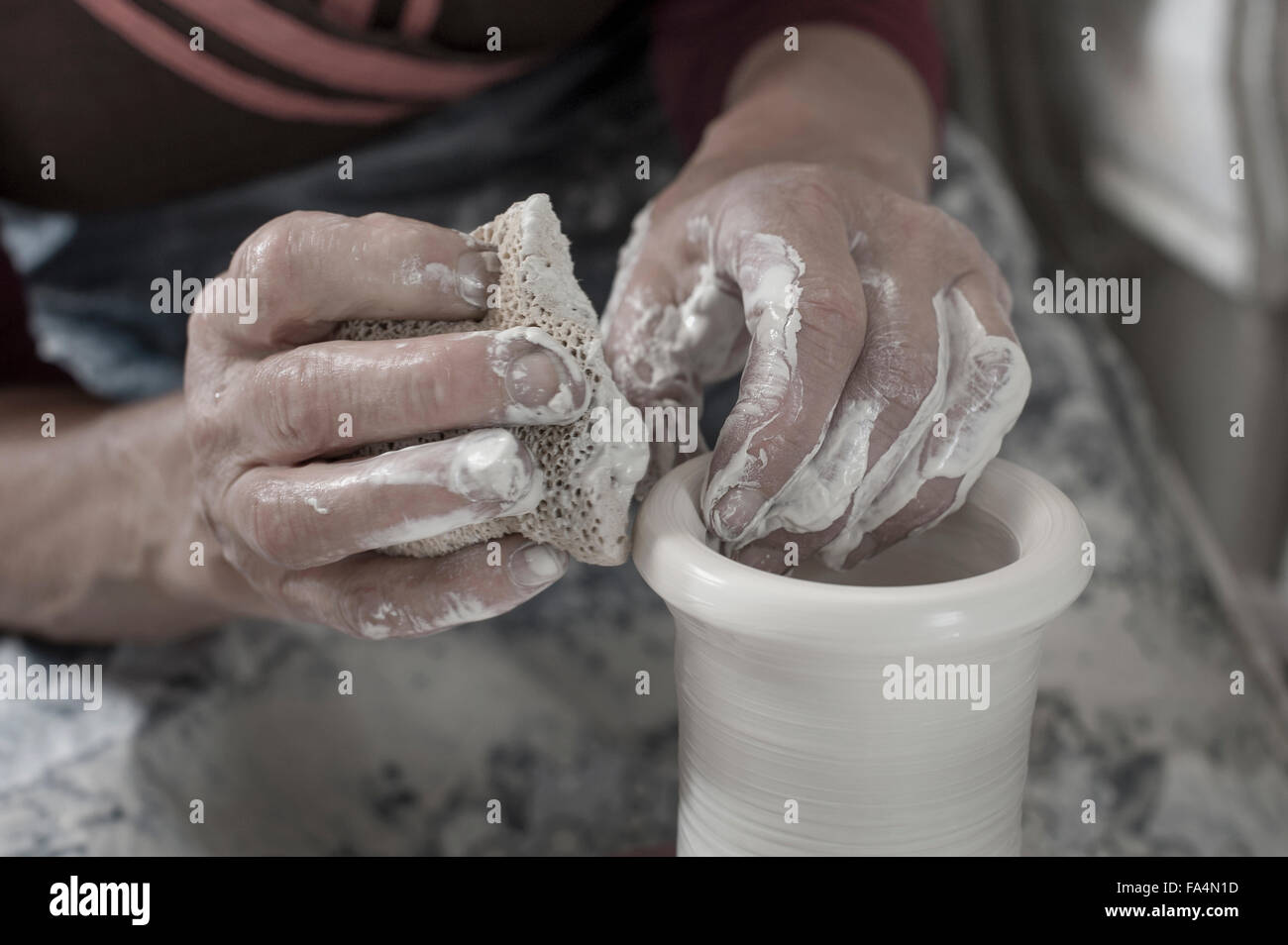 Nahaufnahme von weiblichen Potter Formen Ton mit Reinigungsschwamm in Werkstatt, Bayern, Deutschland Stockfoto