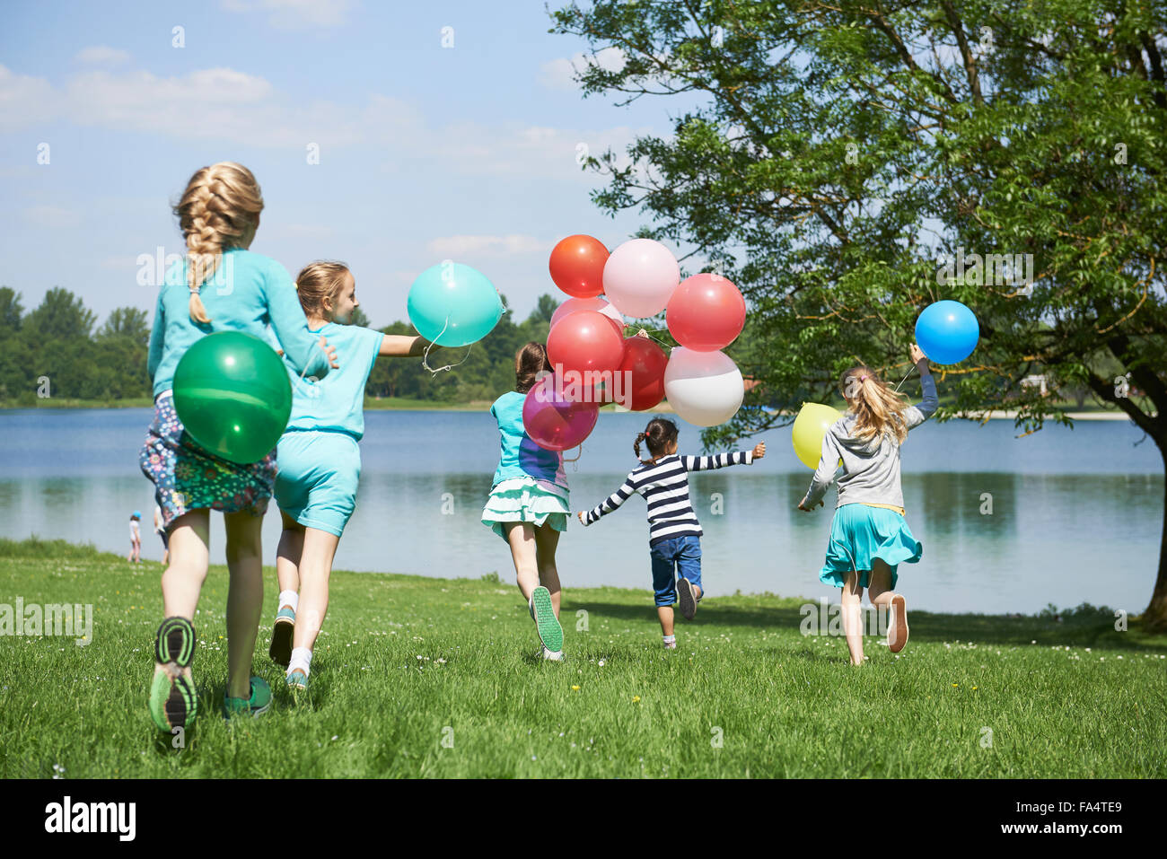 Rückansicht des Mädchen laufen im Park mit Luftballons, See Karlsfeld, München, Bayern, Deutschland Stockfoto