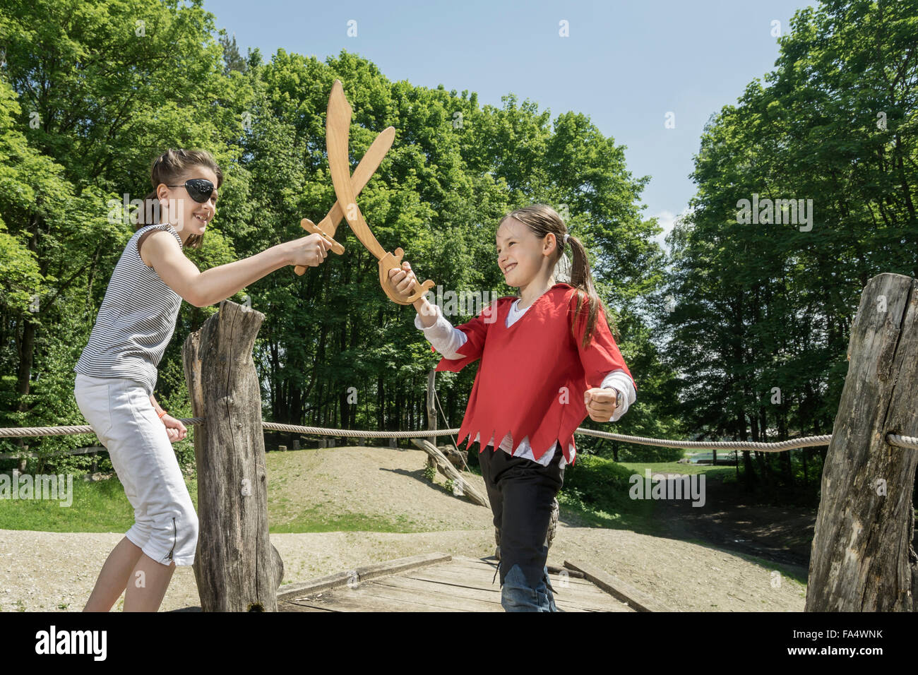 Zwei Mädchen, so zu tun als Piraten kämpfen mit Schwertern in Abenteuer Spielplatz, Bayern, Deutschland Stockfoto