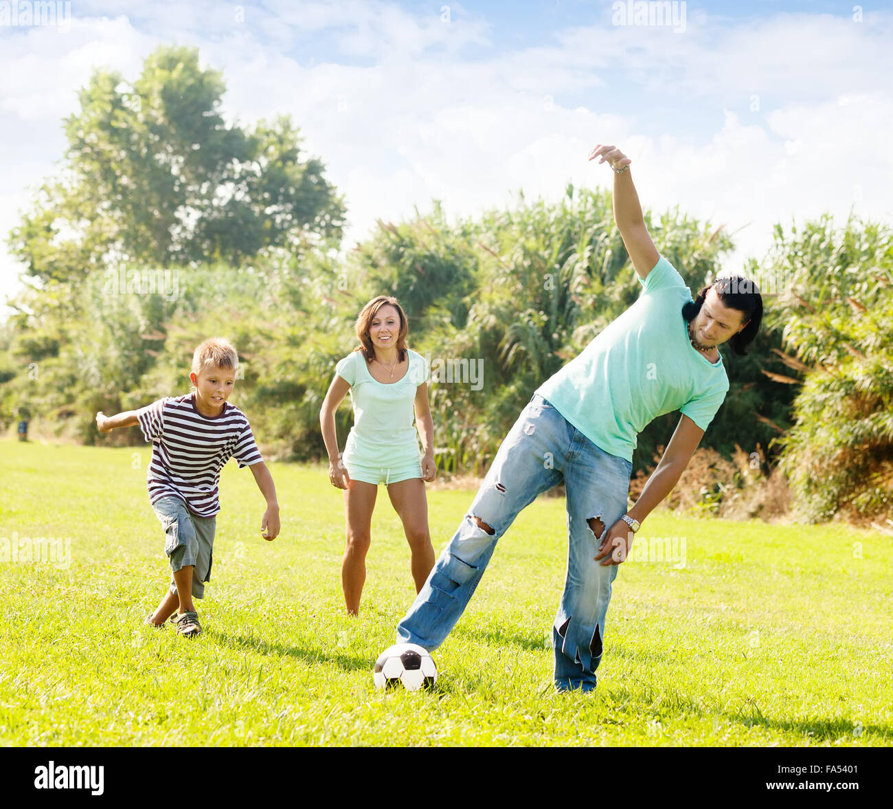 Glückliche Familie mit Teenager spielen mit Fußball im Sommerpark Stockfoto