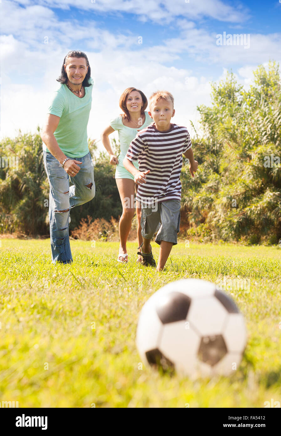 Glückliches Paar mit Sohn spielen mit Fußball im Sommerpark Stockfoto