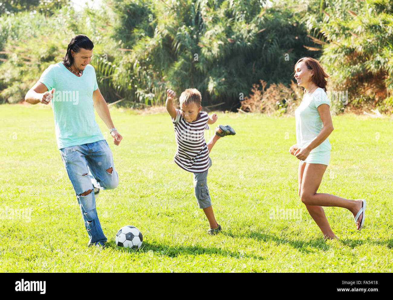 Paar mittleren Alters und Teenager spielen mit Fußball im Sommerpark Stockfoto